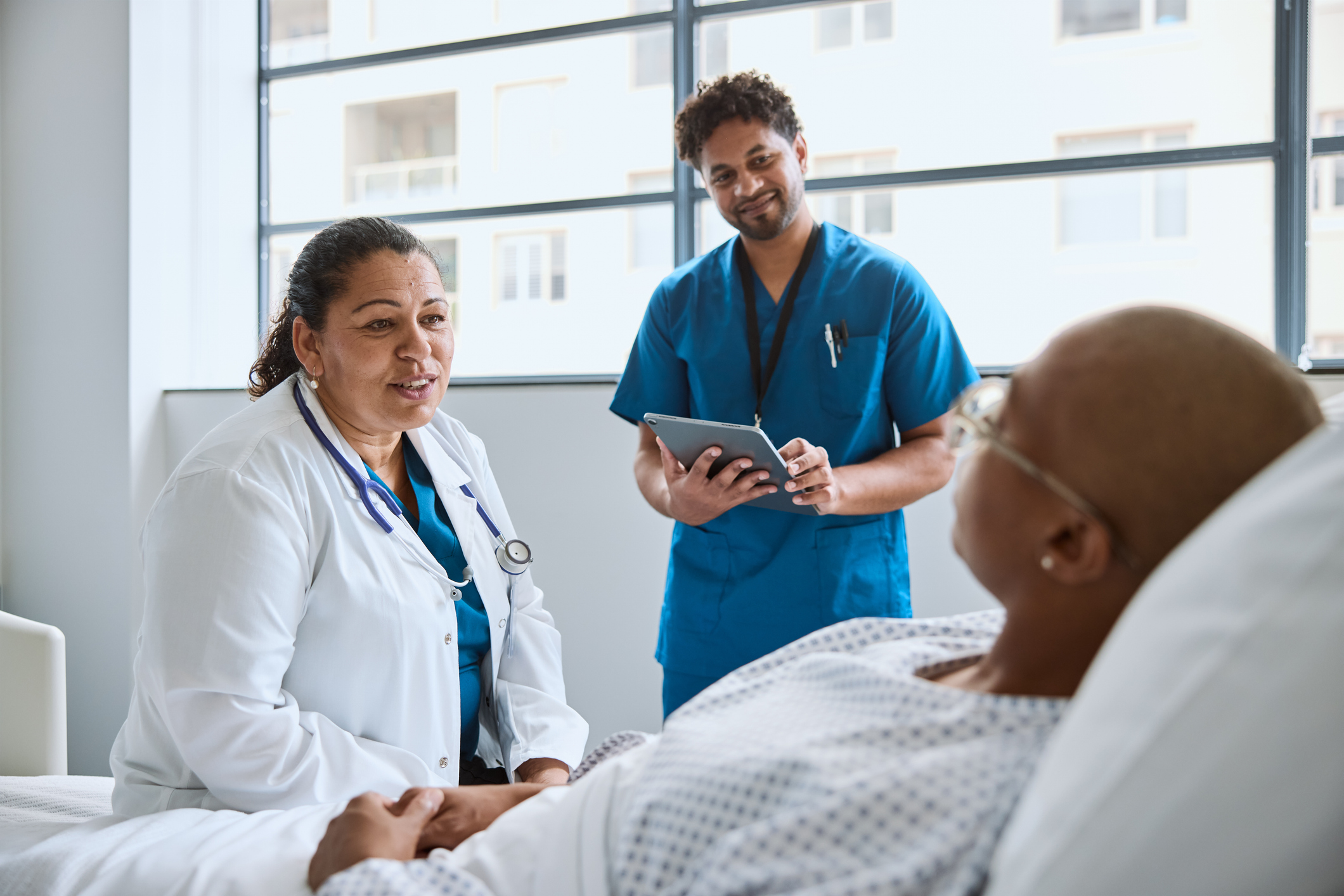 Smiling Female Doctor Sitting Next To Woman In Clinic